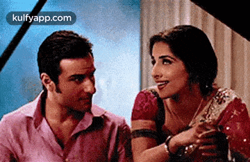 a man and a woman are sitting next to each other and smiling .