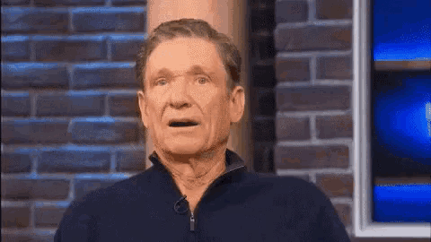 a man is standing in front of a brick wall and making a funny face .