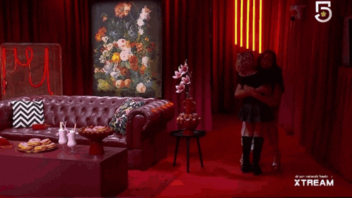 a man and woman are hugging in a living room with a sign that says xstream on it