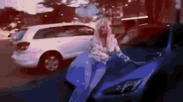 a woman is sitting on a blue motorcycle next to a car .