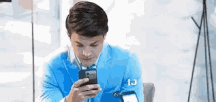 a man in a blue suit is using his cell phone .
