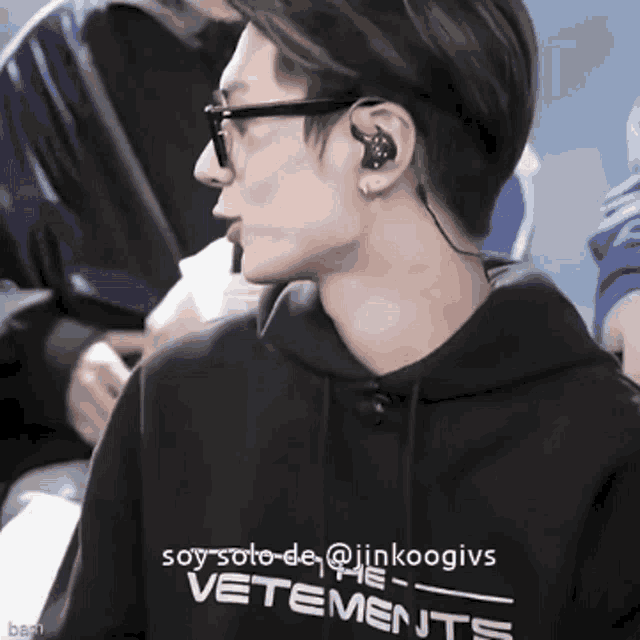 a man wearing glasses and headphones is wearing a vetements hoodie