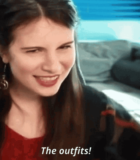 a woman is smiling and saying the outfits while sitting on a couch