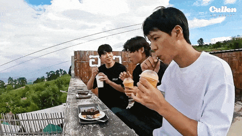 three young men are sitting at a table eating and drinking with the word cullen in the background