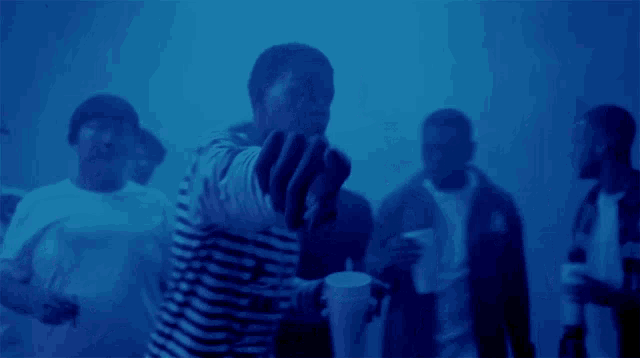 a man in a striped shirt is holding a cup in front of a group of people