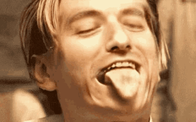 a close up of a man sticking out his tongue .