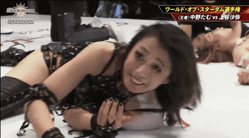 a female wrestler is laying on the ground with a stardom logo above her