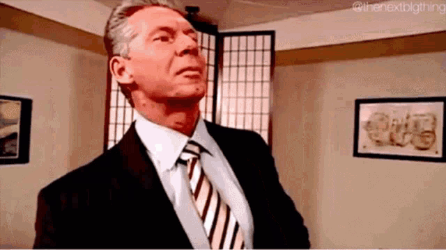 a man in a suit and tie is looking up in a room with pictures on the wall .