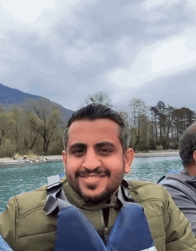 a man wearing a life jacket smiles while sitting in a boat