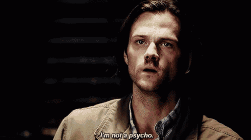 a man with long hair and a beard is saying i 'm not a psycho in a dark room .