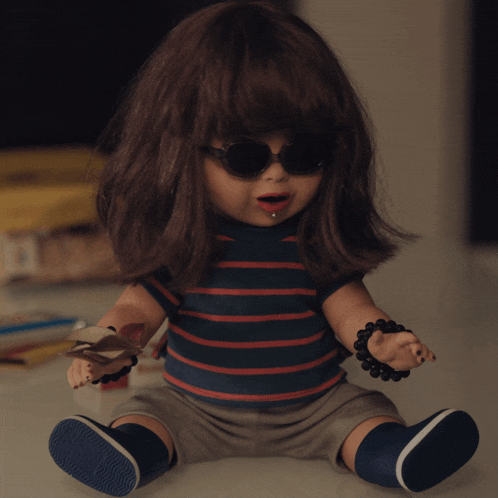 a doll wearing sunglasses and a striped shirt is sitting on a table