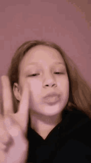 a young girl is making a peace sign with her hands .