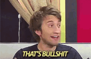 a man in a black shirt is saying `` that 's bullshit '' while sitting on a couch .