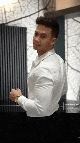 a man in a white shirt is standing in front of a window