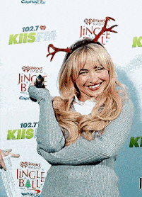 a woman wearing a reindeer headband is smiling and holding a microphone