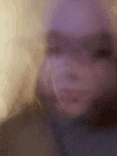 a blurry picture of a woman 's face with a purple hat on