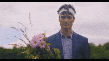 a man in a suit holds a bouquet of pink flowers