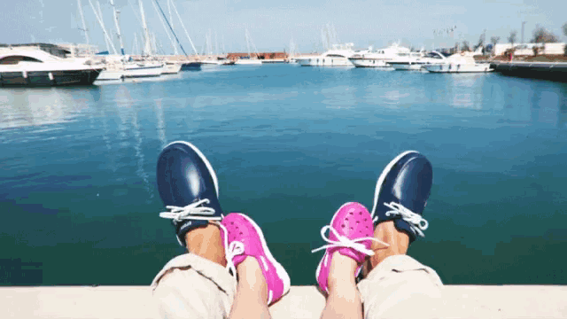 a person wearing a pair of pink shoes sits next to a person wearing blue shoes