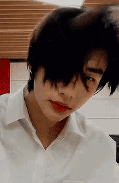 a close up of a person 's face with black hair and a white shirt on .