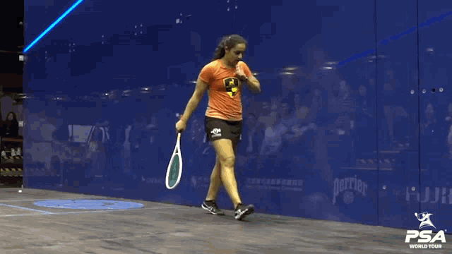 a woman holding a tennis racquet in front of a wall with psa world tour written on it