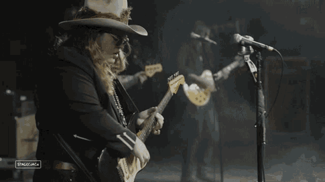 a man in a cowboy hat is playing a guitar and singing into a microphone that says stagecoach