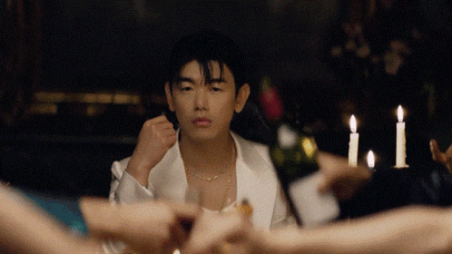 a man sitting at a table with candles and a bottle of wine