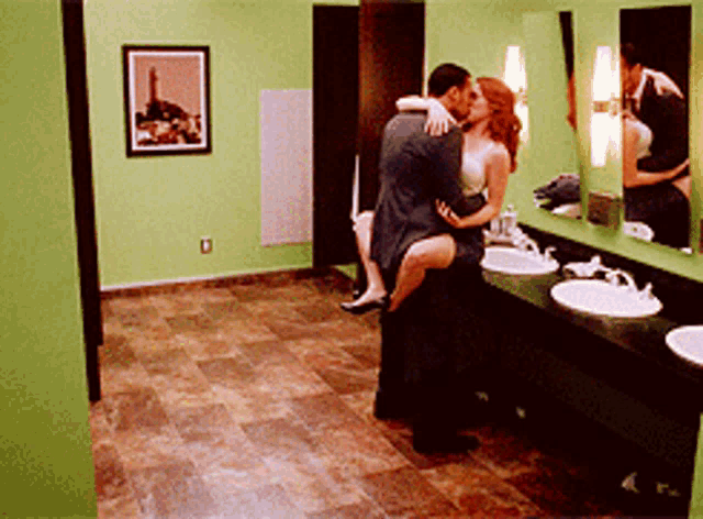 a man and a woman kissing in a public restroom