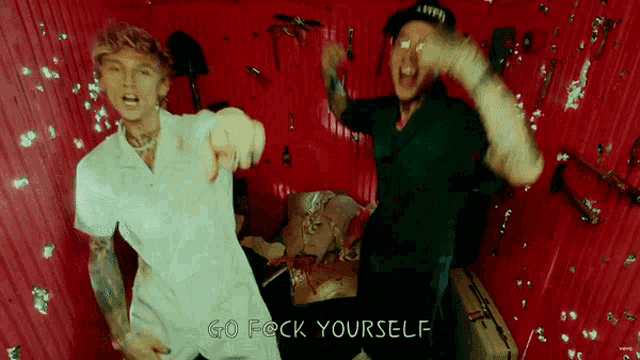 two men are dancing in a room that says go f * ck yourself on it