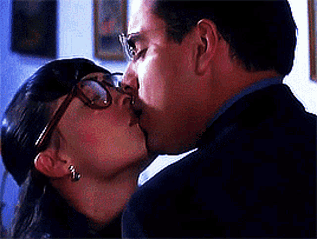 a man and a woman are kissing with glasses on