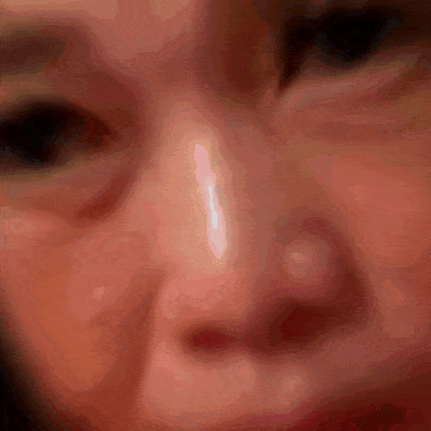 a close up of a woman 's face with a white spot on her nose