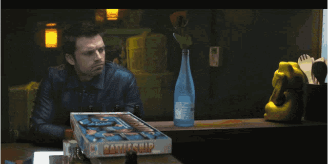 a man sits at a table with a battleship game on it