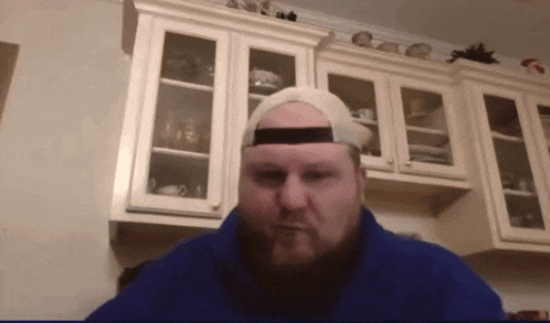 a man with a beard wearing a hat and a blue jacket