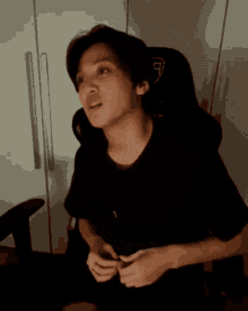 a man in a black shirt is sitting in a chair and looking at something .