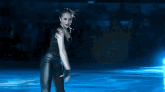 a woman in a black top and pants is dancing on ice .