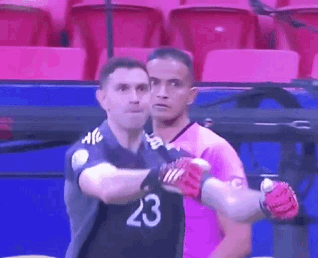 a man in a purple shirt with the number 20 on it is standing next to another man .