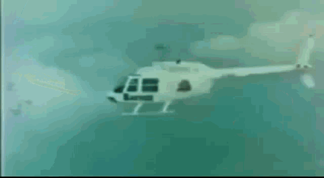 a white helicopter is flying through a cloudy sky