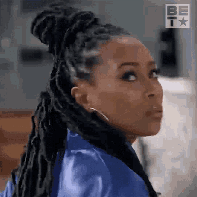 a woman with dreadlocks is wearing a blue robe and earrings