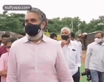 a man wearing a mask is walking in a crowd of people .