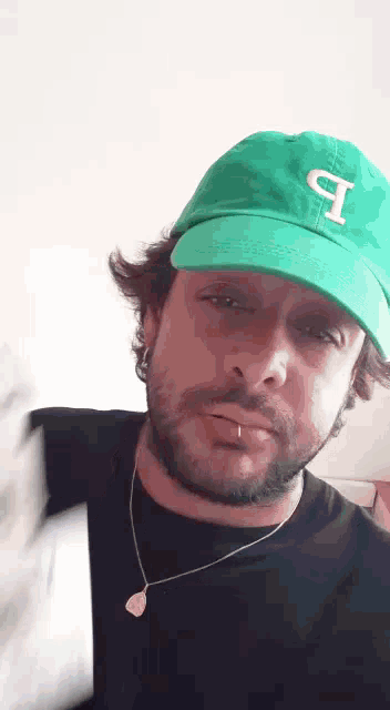 a man with a beard wearing a green hat with the letter p on it