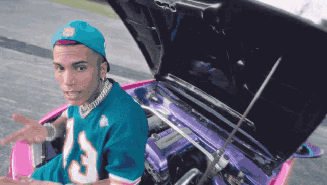 a man wearing a miami dolphins jersey sits in a pink car