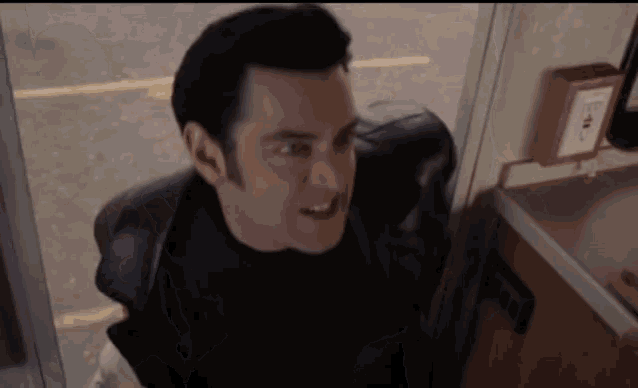 a man in a black jacket stands in a room
