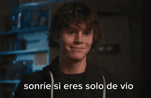 a young man with curly hair is smiling with the words sonrie si eres solo de vio behind him