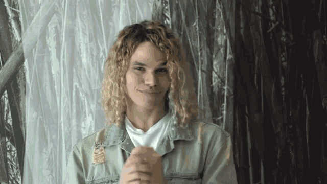 a man with long blonde curly hair is clapping his hands