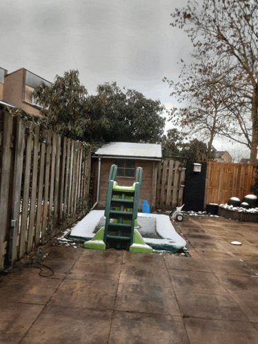 a backyard with a wooden fence and a slide