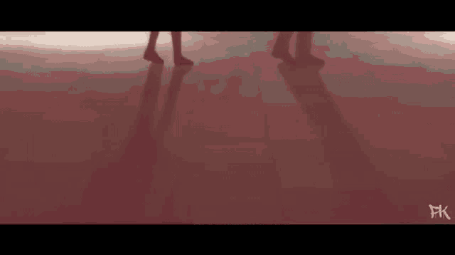 two people are dancing on a red floor with their shadows on the floor .