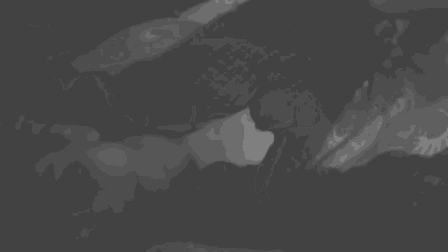 a black and white photo of a person laying on a bed with smoke coming out of their mouth .
