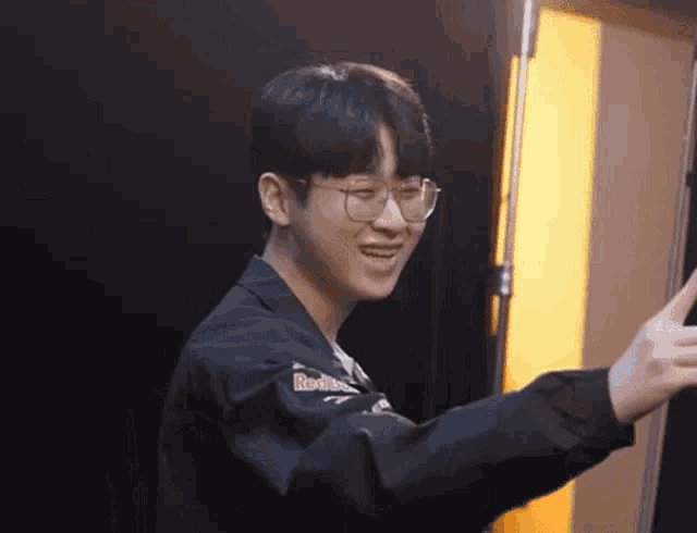 a young man wearing glasses and a jacket that says red bull on it