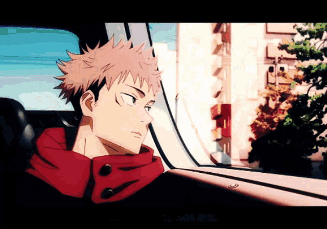 a man in a red jacket is sitting in a car and looking out the window