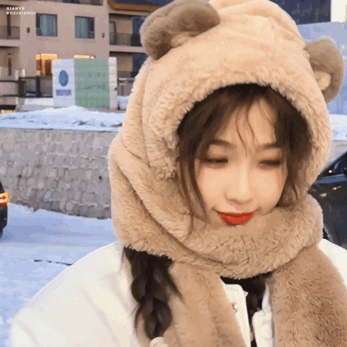 a girl wearing a teddy bear hat and scarf looks at the camera