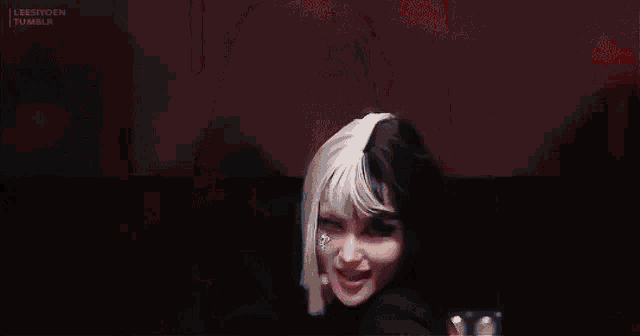 a woman with half black and half white hair is wearing a black turtleneck sweater .
